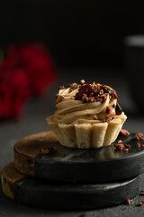 Little cake with candle and smoke with red roses on black table. Mystic dramatic birthday concept. Dark mood greeting birthday card.