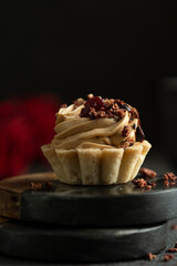 Little cake with candle and smoke with red roses on black table. Mystic dramatic birthday concept. Dark mood greeting birthday card.