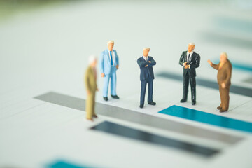 Obraz premium Miniature businessman standing on the report graph of business direction strategy.