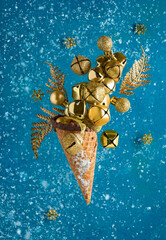 abstract christmas background in blue and gold colors, waffle cone with christmas bells among falling artificial snow