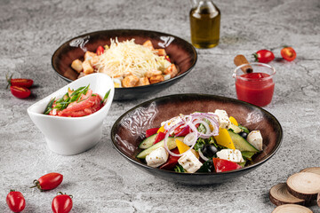 Various appetizing salads greek and caesar on the gray background