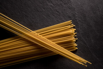 Spaghetti en deux tas croisés, cru , sur fond d'ardoise