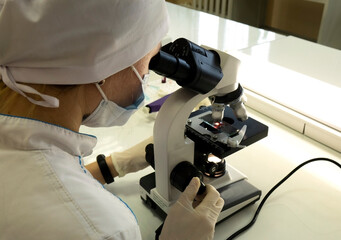 Fototapeta na wymiar A female doctor conducts medical research using a microscope.