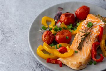 Baked red fish fillet Arctic char on a plate with vegetables close up, delicious hearty healthy...