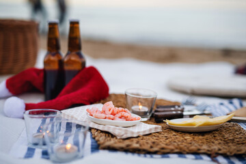Beach picnic with schripms, beer, candles and santa hat. Exotic new year and Christmas
