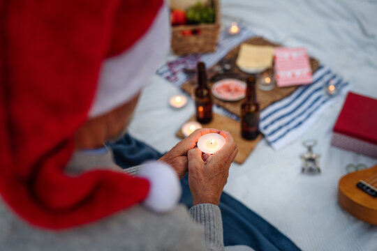 Unrecognizable senior woman in santa hat holding candle and celebrate New Year or Christmas on beach