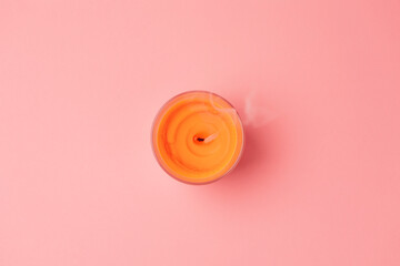 An orange extinguished candle on a pink background. Flat lay. Copy space. The concept of...