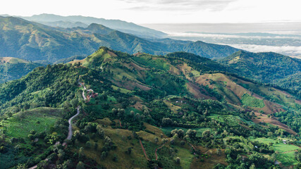 Fototapeta premium Aerial view of sky road over top of mountain with fog and green jungle after raining in morning, doi sakad, Pua, Nan, Thailand. The transportation by road across beautiful mountain. Shot from drone.