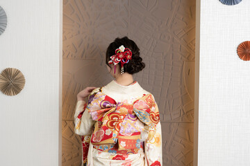 A woman in a kimono with her hand on her left shoulder