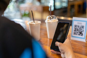 Men use phones to scan a qr code to select a menu or scan to receive a discount or pay for food and...