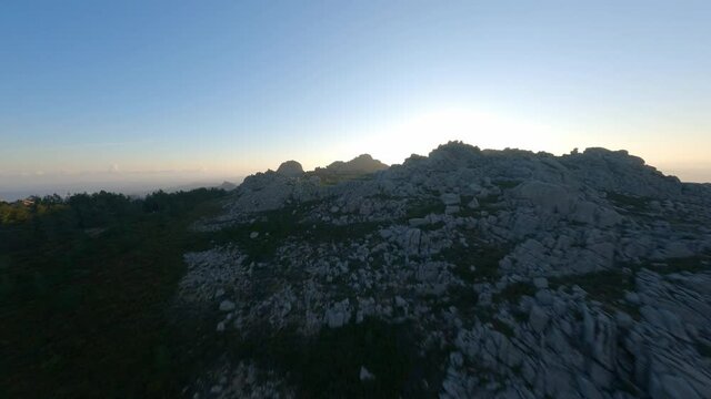 FPV video, mountain surfing, flying at high speed over a granitic mountain range during a beautiful sunrise. Mount Limbara (Monte Limbara) Tempio Pausania, Sardinia, Italy.