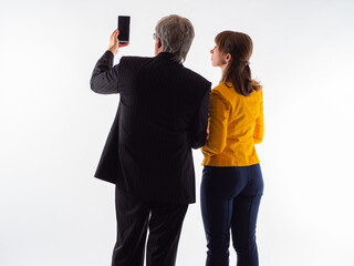 Man gives the woman his phone. Concept - a businessman shows something to an assistant. Man with a girl on white background. Businessmen in a business suit. Business assistant next to him.