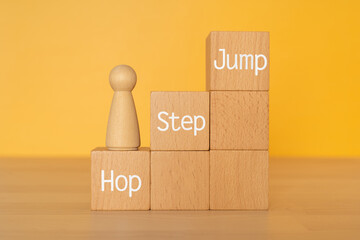 「Hop Step Jump」と書かれた積み木と人形