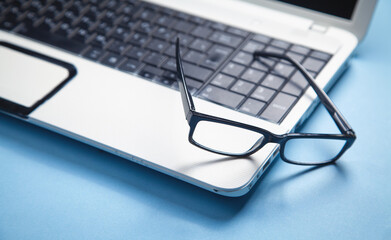 Black eyeglasses on the laptop keyboard.