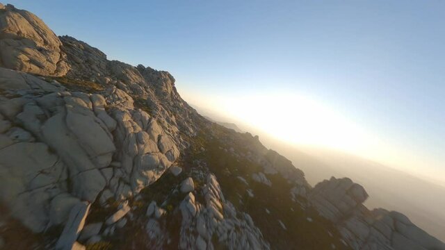 FPV video, mountain surfing, flying at high speed over a granitic mountain range during a beautiful sunrise. Mount Limbara (Monte Limbara) Tempio Pausania, Sardinia, Italy.