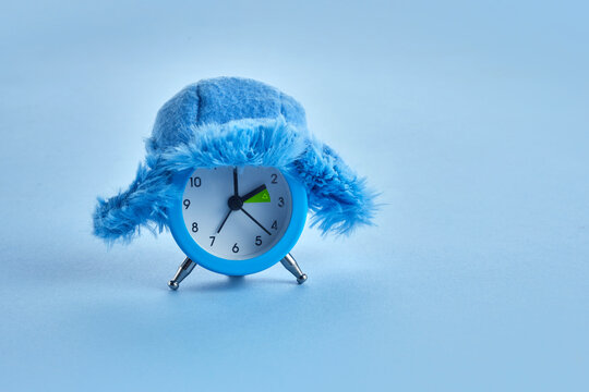Clock changing from summer to winter time. Alarm clock with winter hat