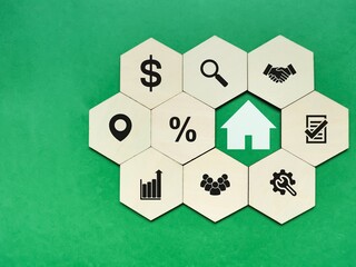 Wooden hexagon with real estate and mortgage icons against green background.