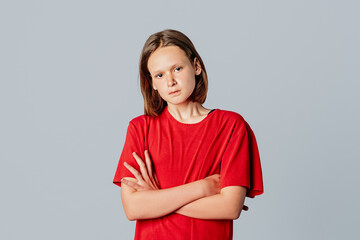 Angry-looking teen girl in casual red t shirt, sulking frowning upset, cross arms chest waiting...
