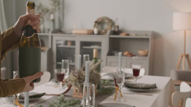 Low Angle Of Cropped Person Pouring Sparkling Wine From Bottle Into Glass On Festive Table Decorated For Christmas At Daytime