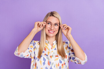 Photo of pretty charming young woman wear print shirt arms spectacles smiling looking empty space isolated violet color background