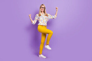 Fototapeta na wymiar Photo of charming lucky young woman wear print shirt spectacles smiling walking rising fists isolated violet color background