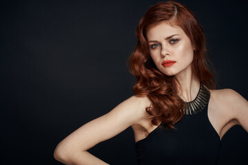 Fototapeta na wymiar attractive red-haired woman in a black dress hairstyle dark background