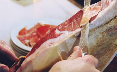 Manos de un profesional cortando jamón ibérico. Jamón ibérico, producto delicioso y tradicional de la cultura española elaborado procedente del cerdo ibérico.