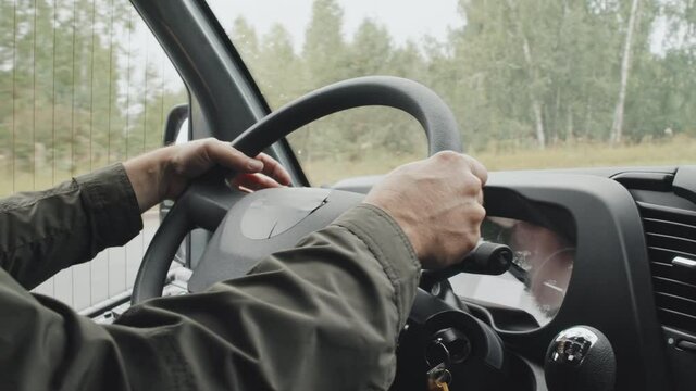 Close-up of unrecognizable male bus driver holding hands on steering wheel during ride