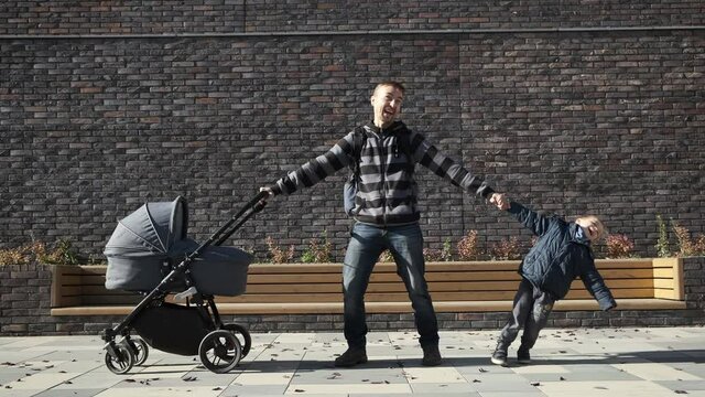 Man in maternity leave concept. Funny exhausted father torn between his little son and newborn in baby stroller.