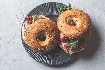 Thanksgiving food concept. Bagel sandwich with turkey and cranberry sauce on a gray plate.