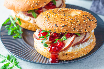 Thanksgiving food concept. Bagel sandwich with turkey and cranberry sauce on a gray plate.