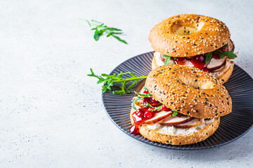 Thanksgiving food concept. Bagel sandwich with turkey and cranberry sauce on a gray plate.