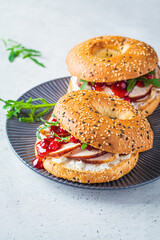 Thanksgiving food concept. Bagel sandwich with turkey and cranberry sauce on a gray plate.