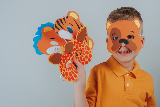Child in a bear mask holds a set in his hand. Set of assorted animal masks, DIY toys, dress up costumes mask, party supplies, birthday party favors, play accessories, photo booth props for kids