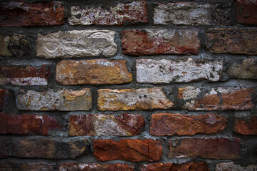 Grey white black red orange old vintage brick wall background. Rustic cemented dark brick house wall texture with grunge surface. Shabby Building Facade With Damaged Plaster. Aged weathered exterior
