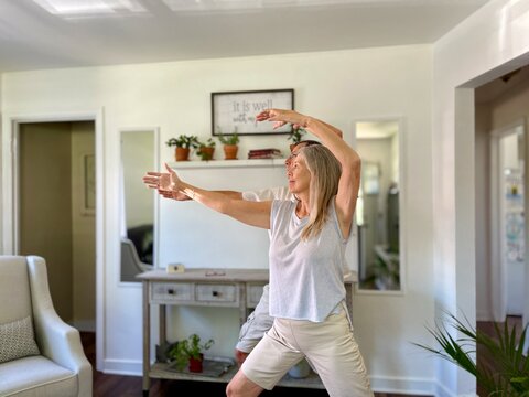 Active Seniors Couple Mirroring One Anothers Movements As They Exercise With Tai Chi Inside.