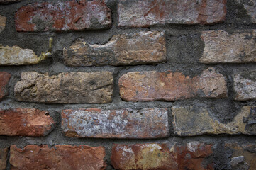 Grey white black red orange old vintage brick wall background. Rustic cemented dark brick house wall texture with grunge surface. Shabby Building Facade With Damaged Plaster. Aged weathered exterior