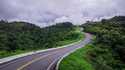 Fototapeta na wymiar Road no.3 or sky road on Root 1081 over top of mountains with green jungle in Santisuk - Bo Kluea District, Nan province, Thailand.
