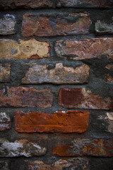 Grey white black red orange old vintage brick wall background. Rustic cemented dark brick house wall texture with grunge surface. Shabby Building Facade With Damaged Plaster. Aged weathered exterior