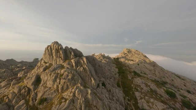 FPV video, mountain surfing, flying at high speed in the clouds with a granitic mountain range and an antenna farm during a beautiful sunrise. Mount Limbara (Monte Limbara) Tempio Pausania, Sardinia, 