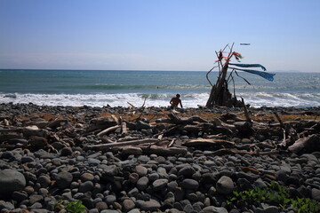 hippy on a sunny beach with wooden shelter teepee with ocean view on a windy day