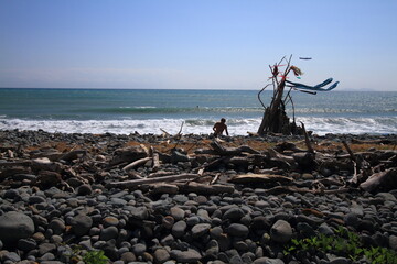 hippy on a sunny beach with wooden shelter teepee with ocean view on a windy day