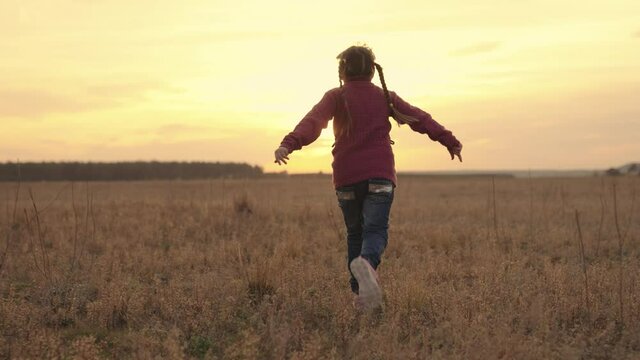 little kid runs with his hands up at sunset in sky, child plays on playing field, happy family, baby fantasizes having fun being pilot, childhood dream fly, girl runs away at dawn pilot improvisation