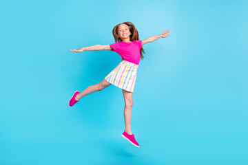 Obraz na płótnie Canvas Full body photo of cheerful happy small girl jump up hands wings plane isolated on blue color background