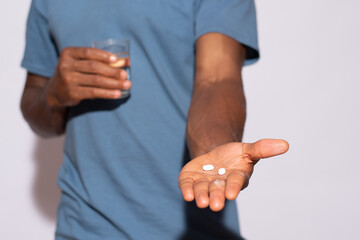 black man holding some medicine and a glass of water