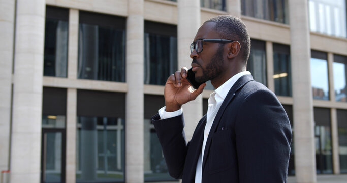 Handsome mixed-race businessman outdoors talking on mobile phone