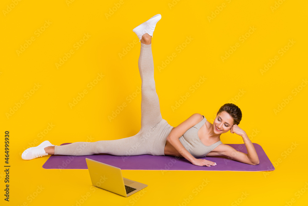 Sticker Photo of flexible lady lay mat stretch legs look pc online training wear cropped top isolated yellow color background