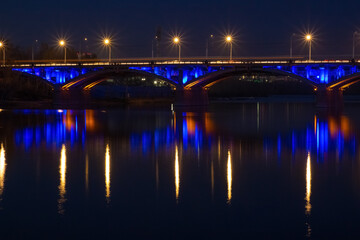 Fototapeta na wymiar Dusk landscape with illuminated Communal bridge through Yenisei River in Krasnoyarsk, Russia. Night city lights