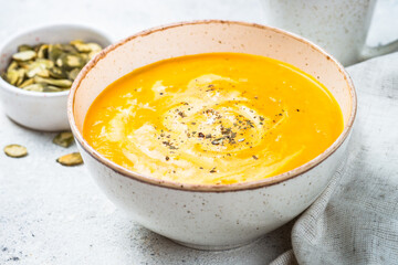 Pumpkin soup puree with cream in the craft bowl. Close up.