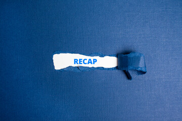 The text  RECAP appearing on white paper behind torn color paper.